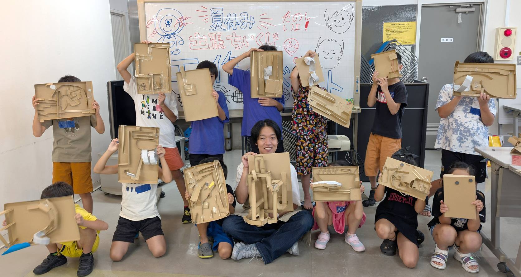 夏休み出張ちいくじ工作教室in亀山で段ボール工作の作品を掲げる子どもたち